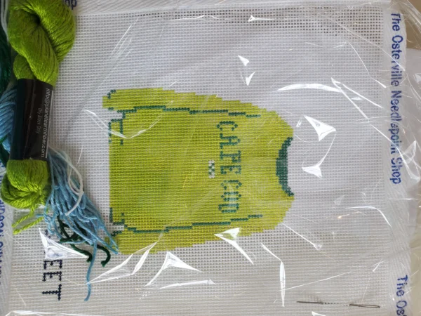 A bag of yarn and a shirt on top of the ground.