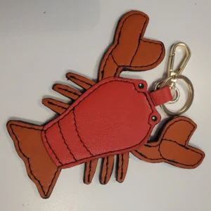 A lobster key chain is shown on top of a table.