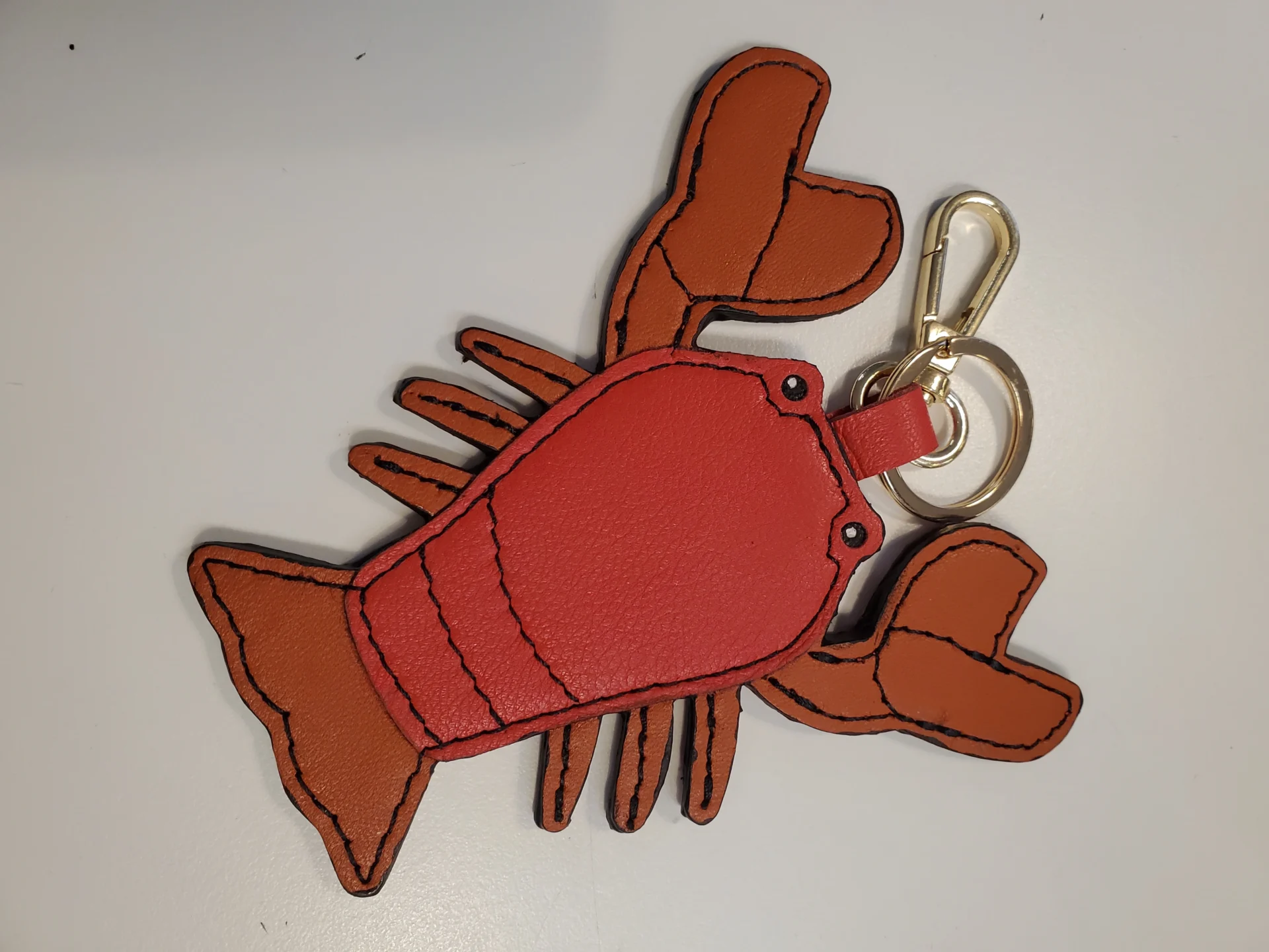 A lobster key chain is shown on top of a table.