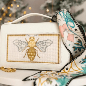 A white purse with a bee design on it.