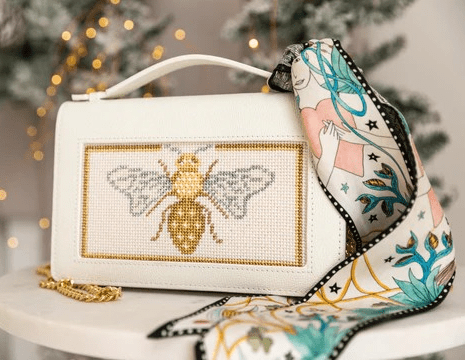 A white purse with a bee design on it.