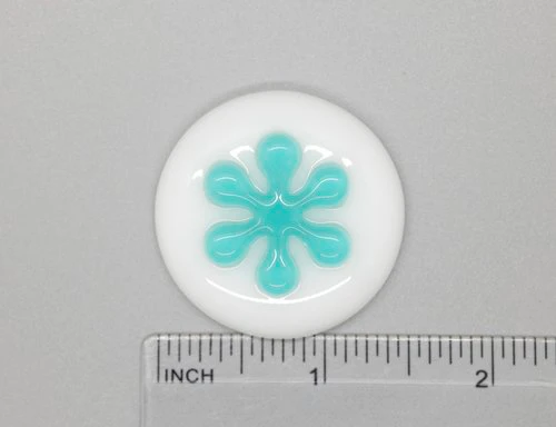 A white button with blue design on it.