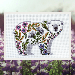 A white bear with purple and pink flowers on it's back.