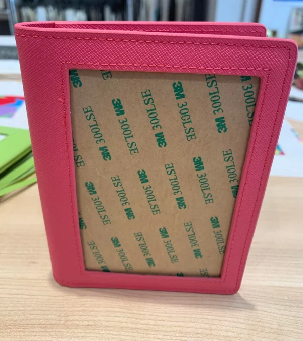 A pink wallet with some green stickers on it