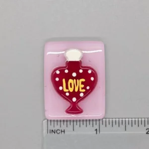 A red heart shaped bottle with the word love on it.