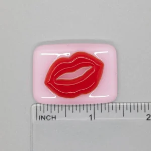 A pink and red lip patch sitting on top of a ruler.