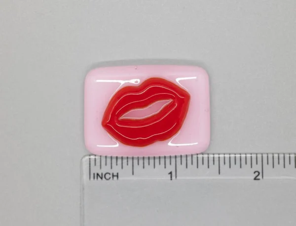 A pink and red lip patch sitting on top of a ruler.