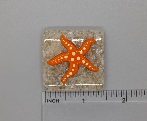 A square shaped tile with an orange starfish on it.