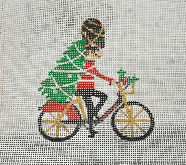 A person riding a bike with a christmas tree on it.