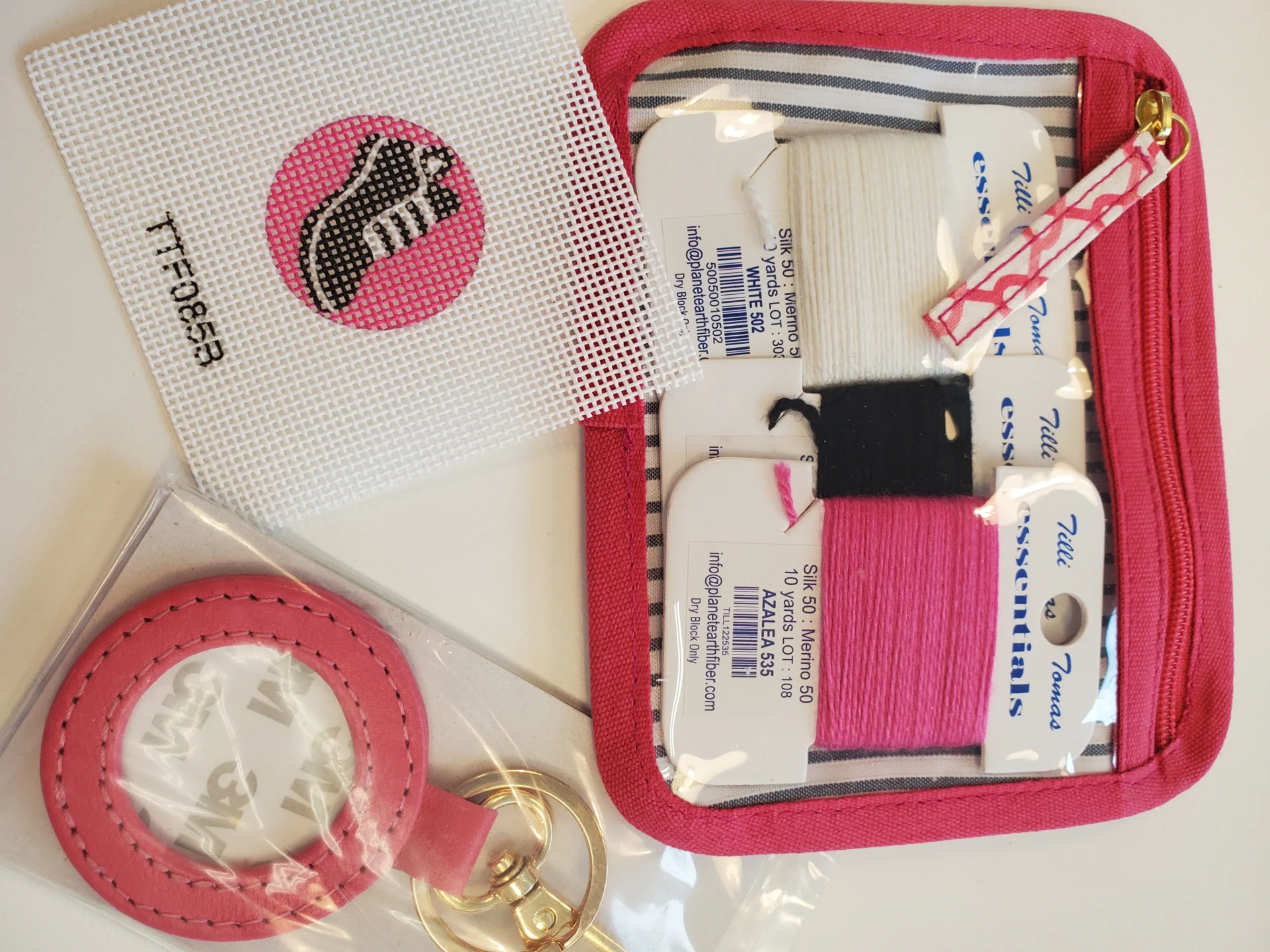 A pink case with some sewing supplies on it