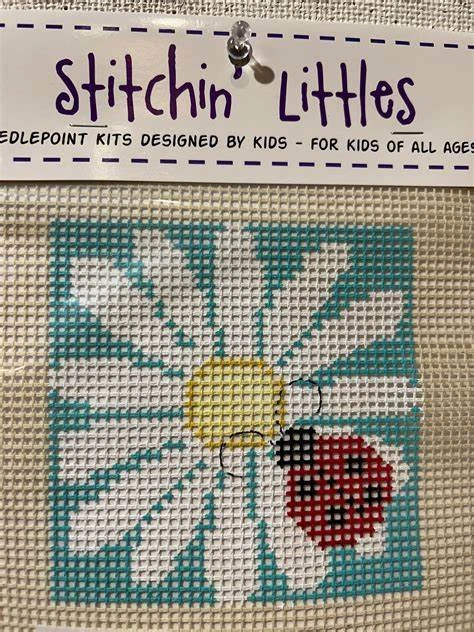 A cross stitch kit with a ladybug and flower.