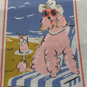 A pink poodle sitting on the beach with a drink.