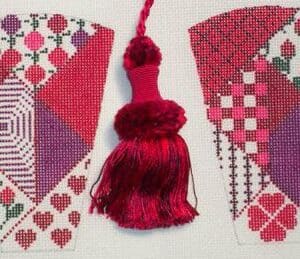 Red tassel between two geometric cross-stitch panels