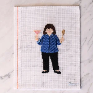 Cross-stitched person holding cocktail and spoon