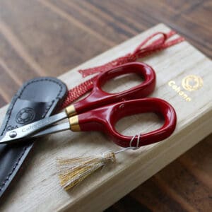 Red-handled embroidery scissors on wooden box