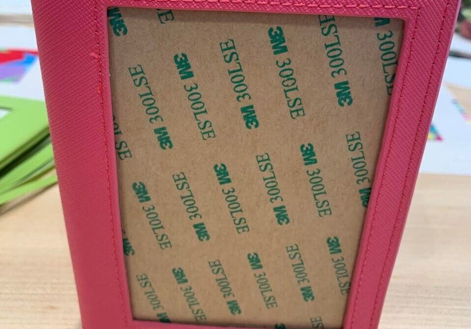 A pink wallet with some green stickers on it